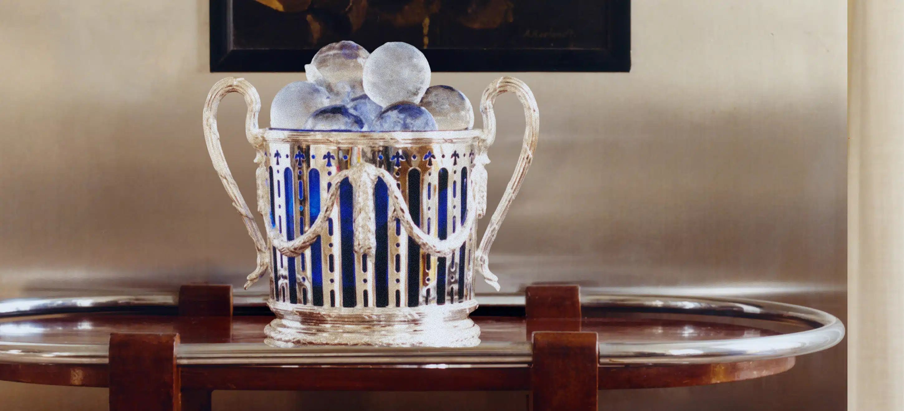 Seau à champagne avec insert en verre bleu de Murano, posé sur une table roulante devant un cadre 
