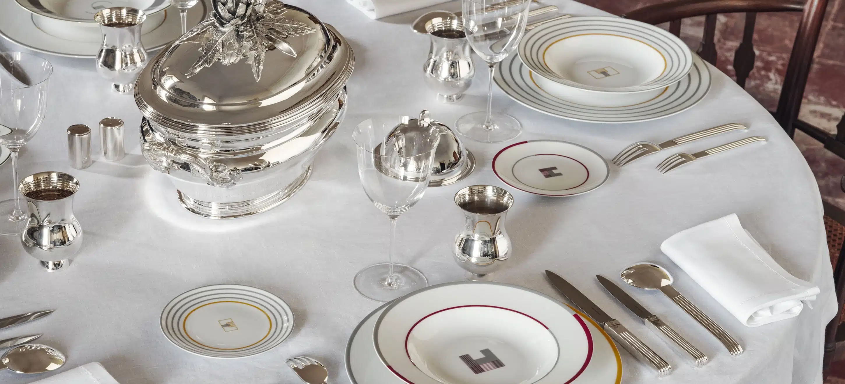 Table dressée de pièces en argent massif et assiettes à pain, creuse et à dîner de la collection Monogrammes de Puiforcat