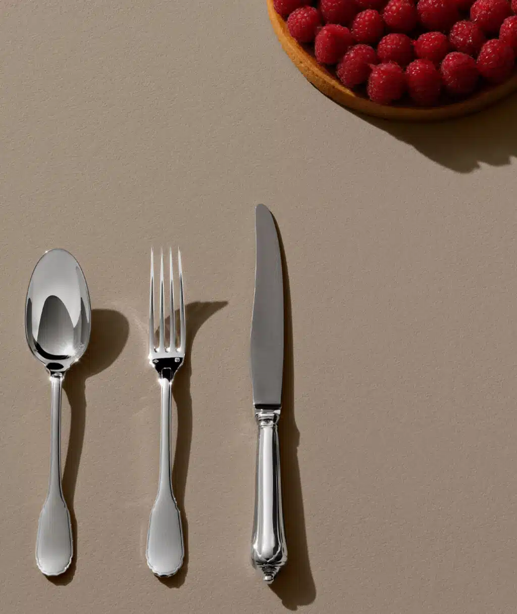 Couverts Noailles sur une table beige avec une amorce de tarte à la framboise en haut à gauche de l'image